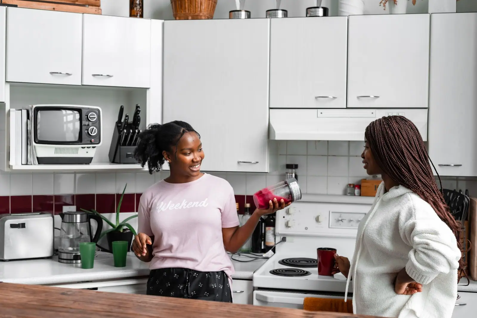 Two adults standing beside kitchen appliances on a counter beneath white cabinets