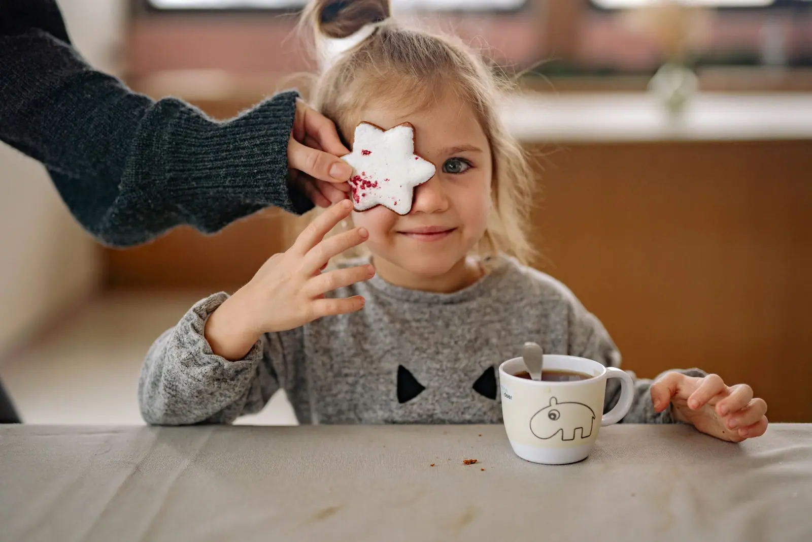 A young child holding a small open cup at a table